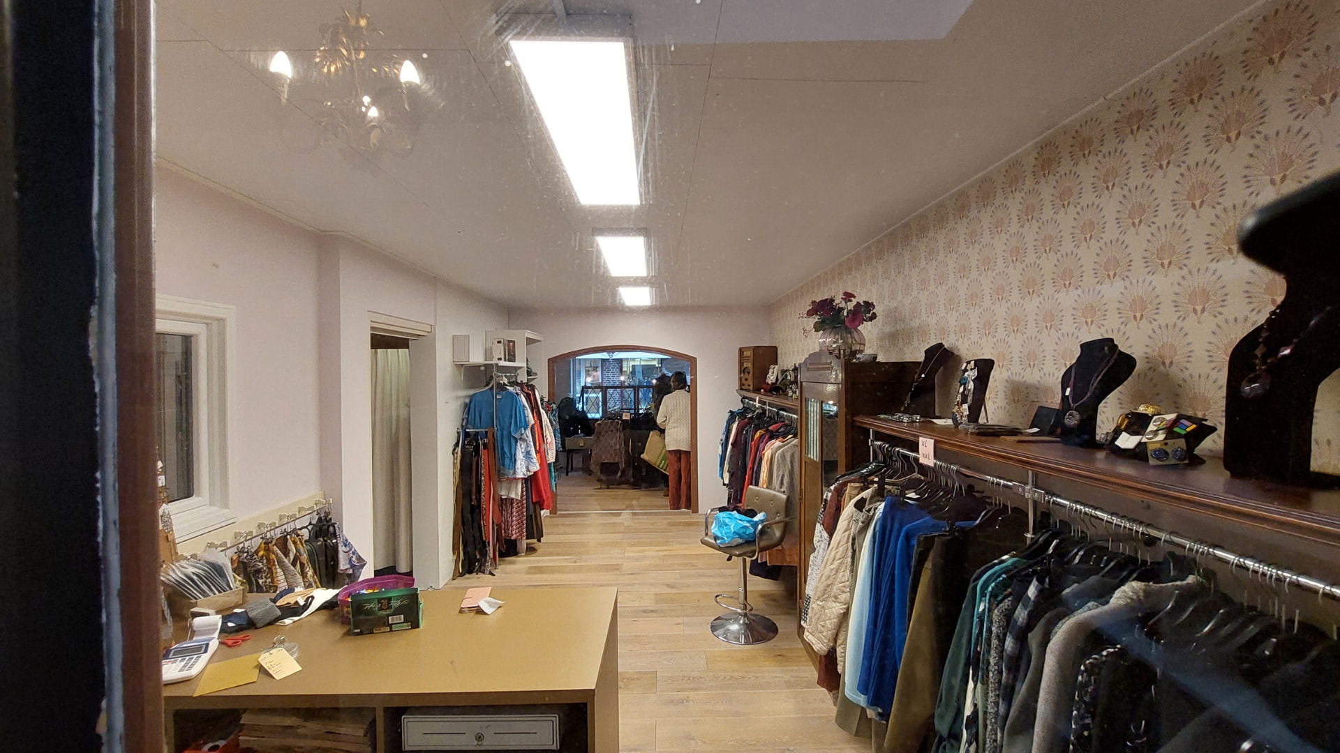 Overzicht van de winkel met kledingrekken en sieraden